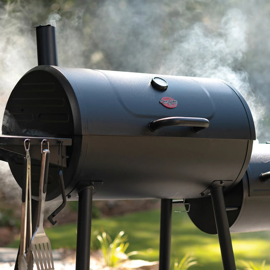 A closed Char-Griller grill with offset smoker. Smoke is billowing out of the side fire box.