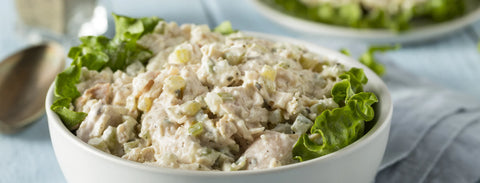 A white bowl lined with a fresh leaf of lettuce and filled with smoked chicken salad