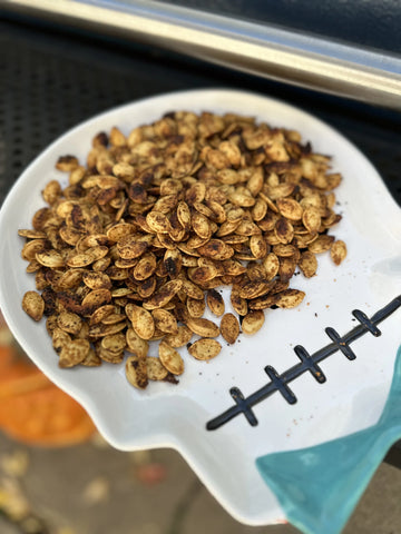 A pile of roasted pumpkin seeds in a white skull plate with a blue bow tie