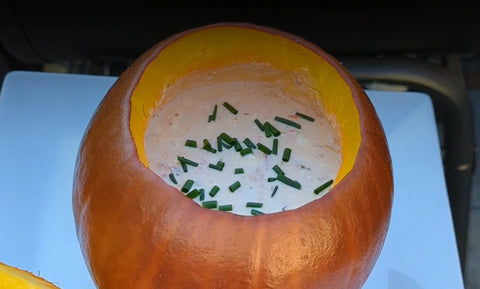 A roasted pumpkin filled with queso dip topped with chopped chives