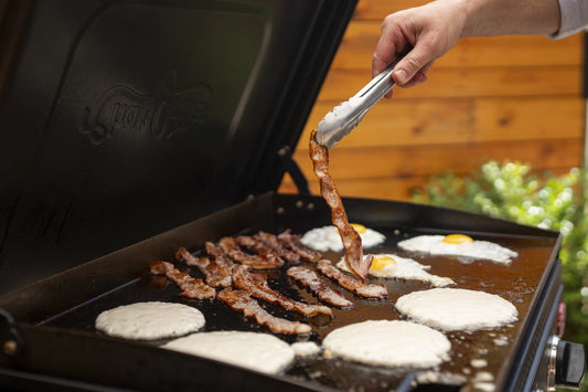 Making breakfast on the outdoor griddle: pancakes, bacon, and eggs.