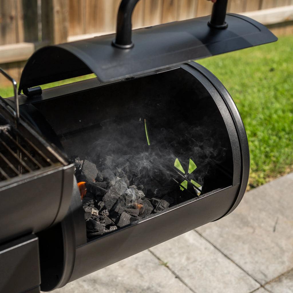 A pile of burning lump charcoal in the base of an offset smoker side fire box.