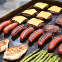 Cheeseburgers, sausages, chicken breasts and asparagus spears cooking on the griddle.