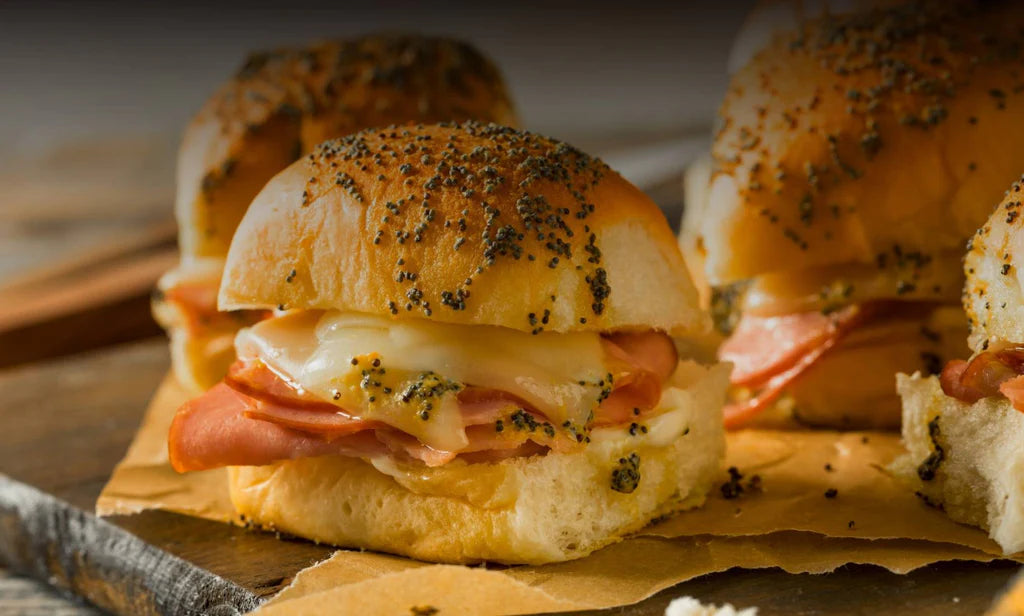 4 poppy-see slider buns filled with sliced ham and melted cheese